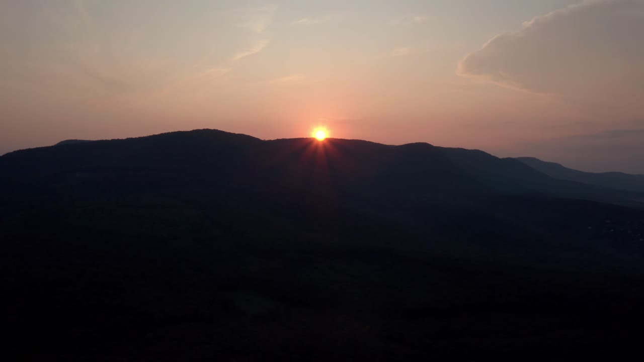 The beautiful orange sun setting behind the mountains in Danube, Europe - Aerial shot