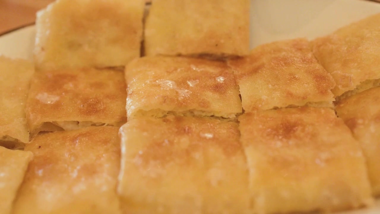 Primo piano di quadrati di roti fritti dorati serviti su un piatto bianco a Bangkok