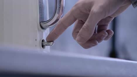 from low angle, a man's hand reaches into frame and turns on the switch of a kettle which lights up red.