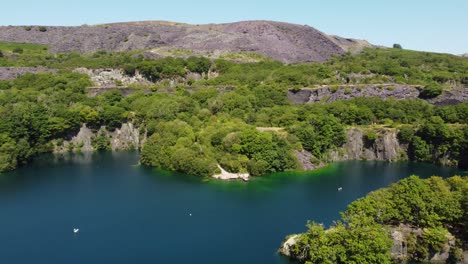 vista aérea dorothea mina de pizarra inundada cantera bosque en el valle de snowdonia con un hermoso lago azul brillante