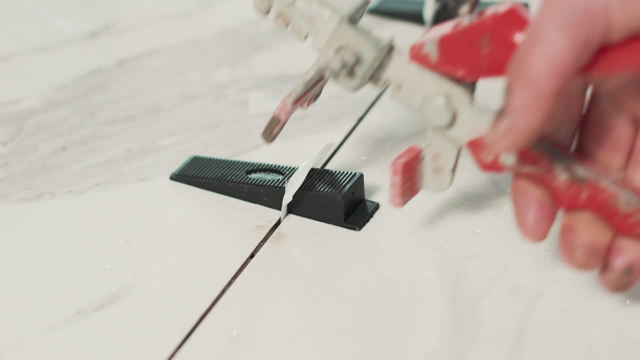 persona colocando cuñas de plástico en baldosas