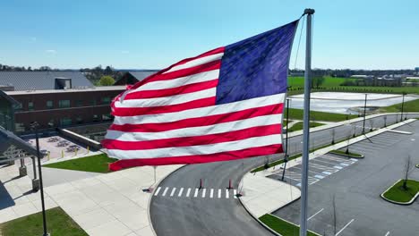 aerial close up of waving american flag in front of school in usa spring season with blue sky and sunny day