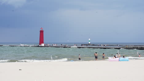 establishing shot red lighthouse in stormy weather on beach