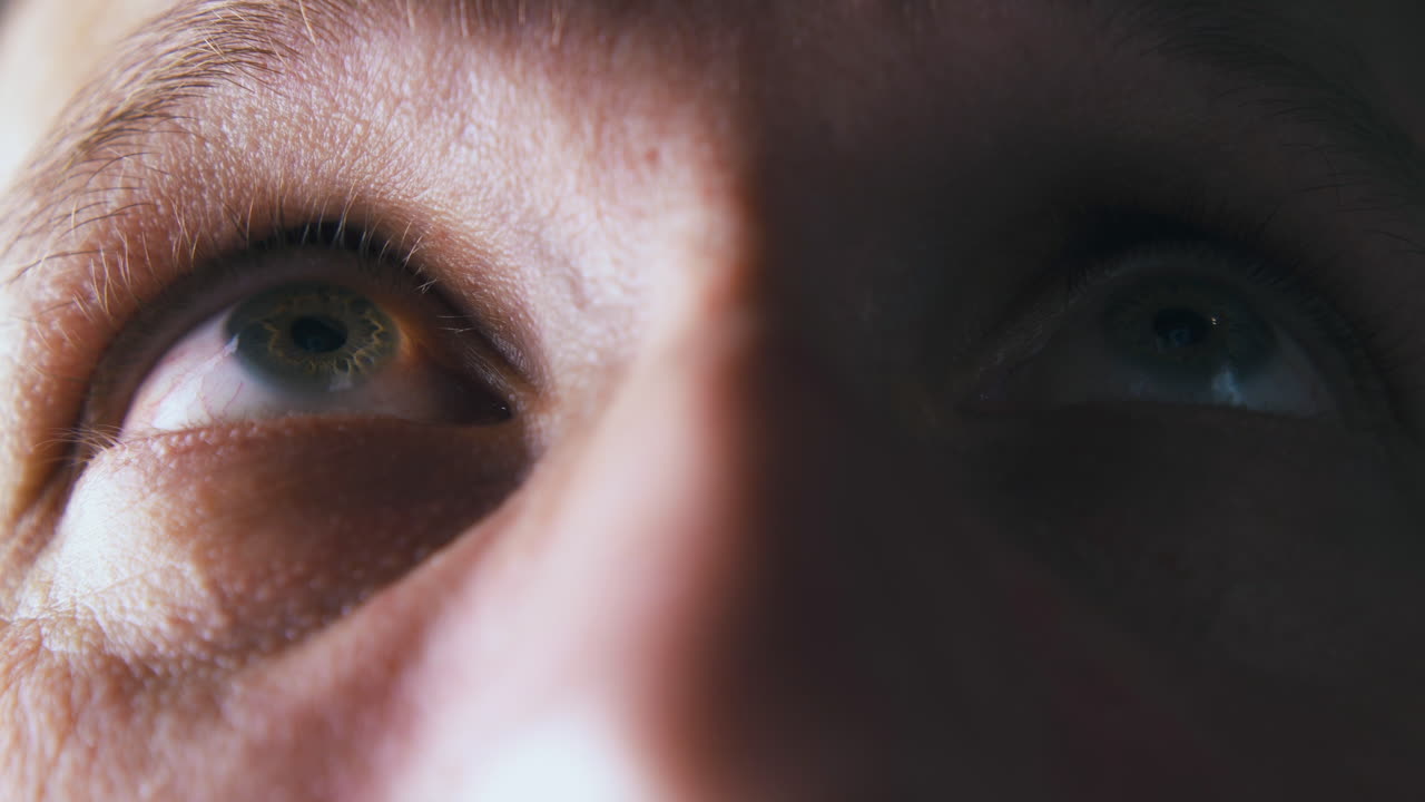 persona mira hacia arriba y recto con el ojo verde en la sombra
