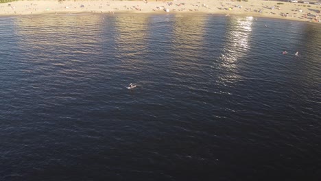 Person-paddle-boarding-near-beach,-orbiting-aerial-view