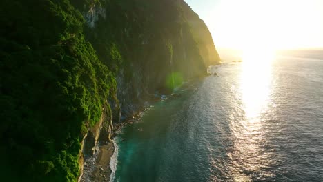 cinematic drone shot of lens flare along coastline of taroko nationalpark with beautiful ocean at sunset,taiwan