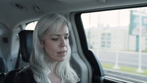 gray haired woman sitting in backseat of moving car