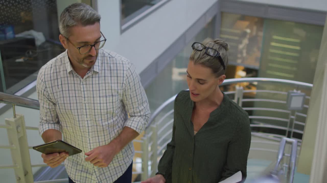 video de una mujer de negocios caucásica y un hombre de negocios caminando por las escaleras y hablando