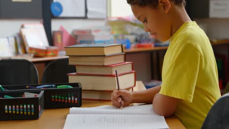 side view of african american schoolboy studying at desk in classroom at school 4k