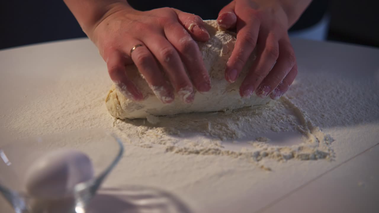 Primo piano di mani che impastano l'impasto su un tavolo infarinato