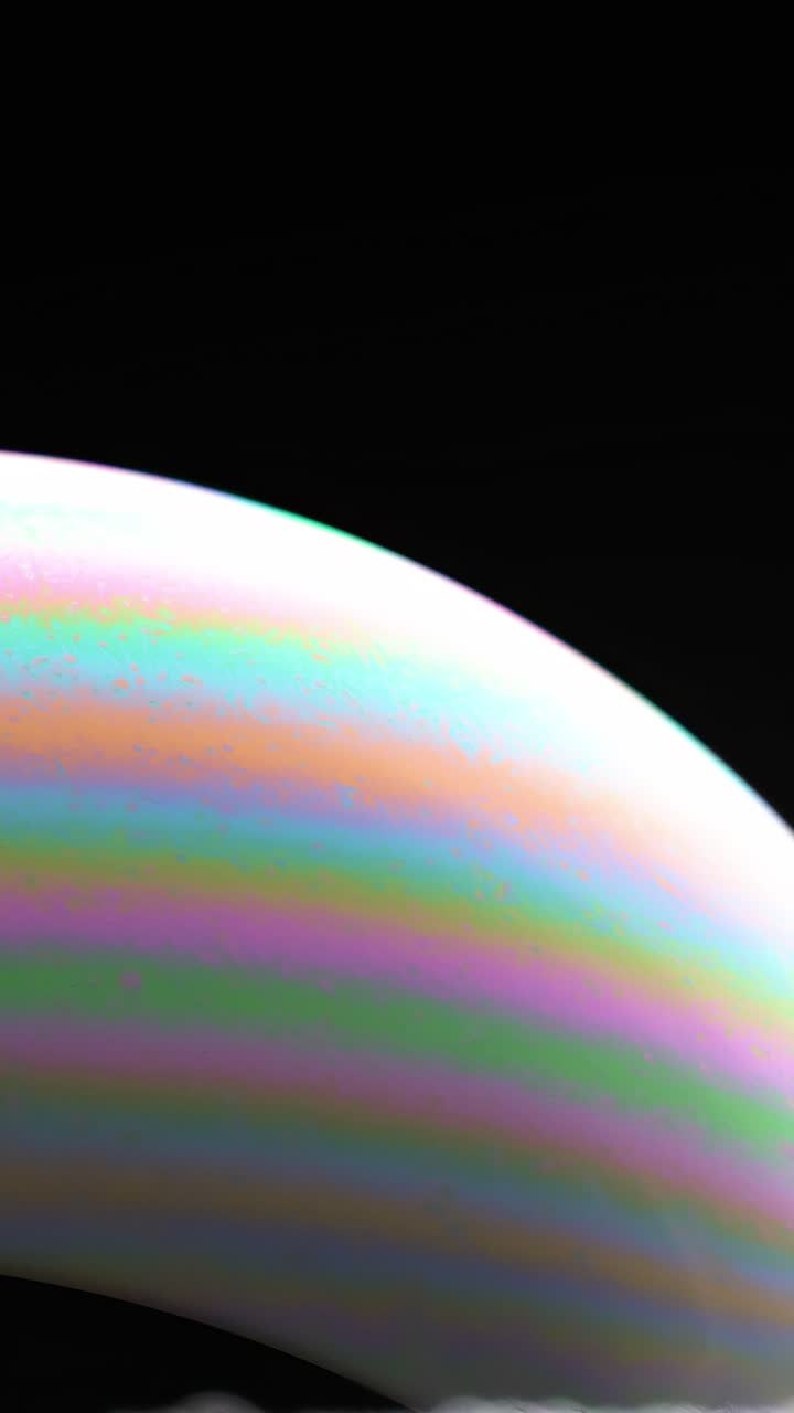 Una bolla di sapone mostra vivaci motivi di colore in una luce cangiante, creando un effetto visivo ipnotizzante.