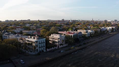 Low-aerial-dolly-shot-over-antebellum-mansions-on-the-waterfront-at-South-Battery-in-Charleston,-South-Carolina-during-sunset