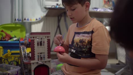 Toma-Mediana-Y-Estática-De-Un-Niño-Caucásico-De-8-Años,-Pintando-Un-Juguete-Planetario-En-Su-Habitación,-Enfoque-Selectivo-De-4k,-Profundidad-De-Campo-Reducida