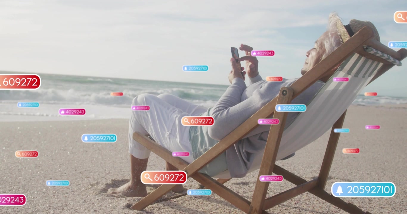 Senior woman beach tapping phone, causing floating badges growing near phone checking social media