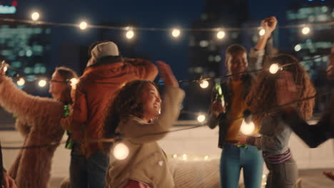 Feliz-Grupo-De-Amigos-Bailando-Juntos-Disfrutando-De-La-Música-De-Fiesta-En-La-Azotea-Por-La-Noche-Divirtiéndose-Bebiendo-Alcohol-Celebrando-La-Reunión-De-Fin-De-Semana