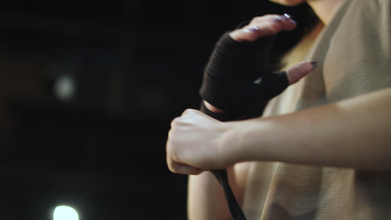 スポーツクラブでボクシングの準備をする女性。手にバンテージを巻く女性のクローズアップ。