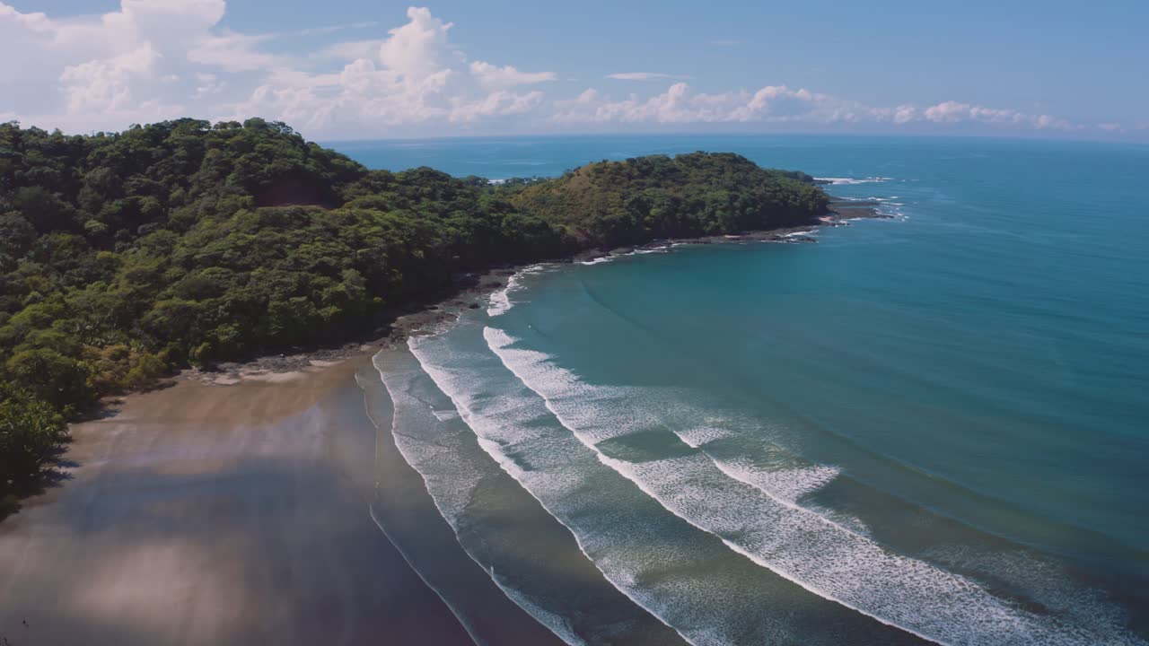 Filmagem aérea de drone 4K UHD de uma praia perfeita e vazia com ondas longas rolando na costa do Oceano Pacífico na Costa Rica em um lindo dia ensolarado