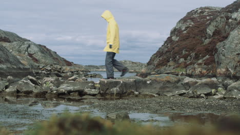 woman in yellow raincoat walks over nature stonebridge