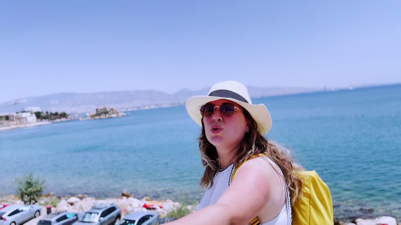 Viajante apontando para o mar do Pireu durante as férias de verão