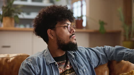 smiling man with curly hair sitting on a couch