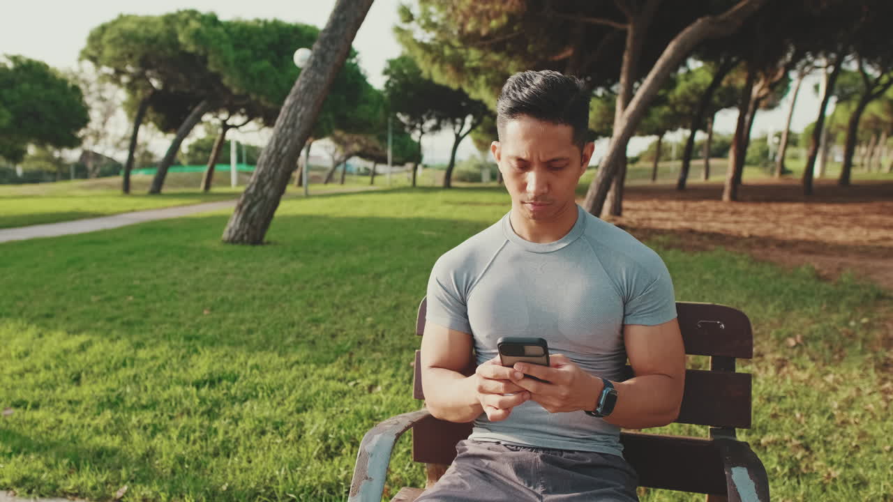 Man sitting on a bench in a park using his phone