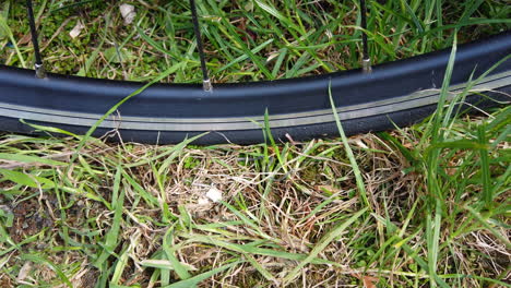 un primer plano de un neumático de bicicleta de carretera delgado que se bombea sobre una superficie cubierta de hierba