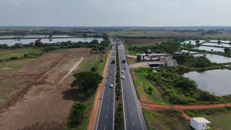 a cinematic aerial shot captures the bustling traffic on the pristine chennai-hyderabad highway, with towering high-voltage power lines casting long shadows across the clean, black asphalt