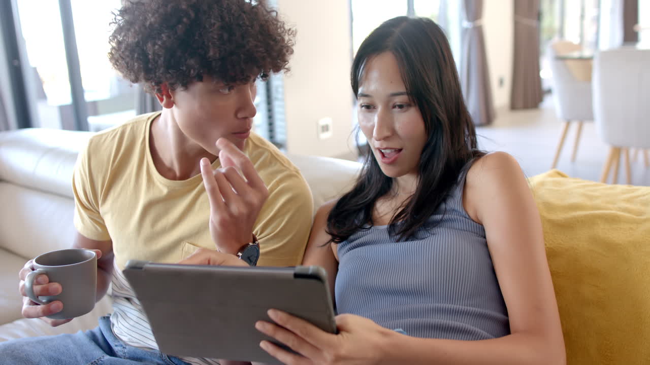 At home, using tablet and drinking coffee, friends hanging out and enjoying time together