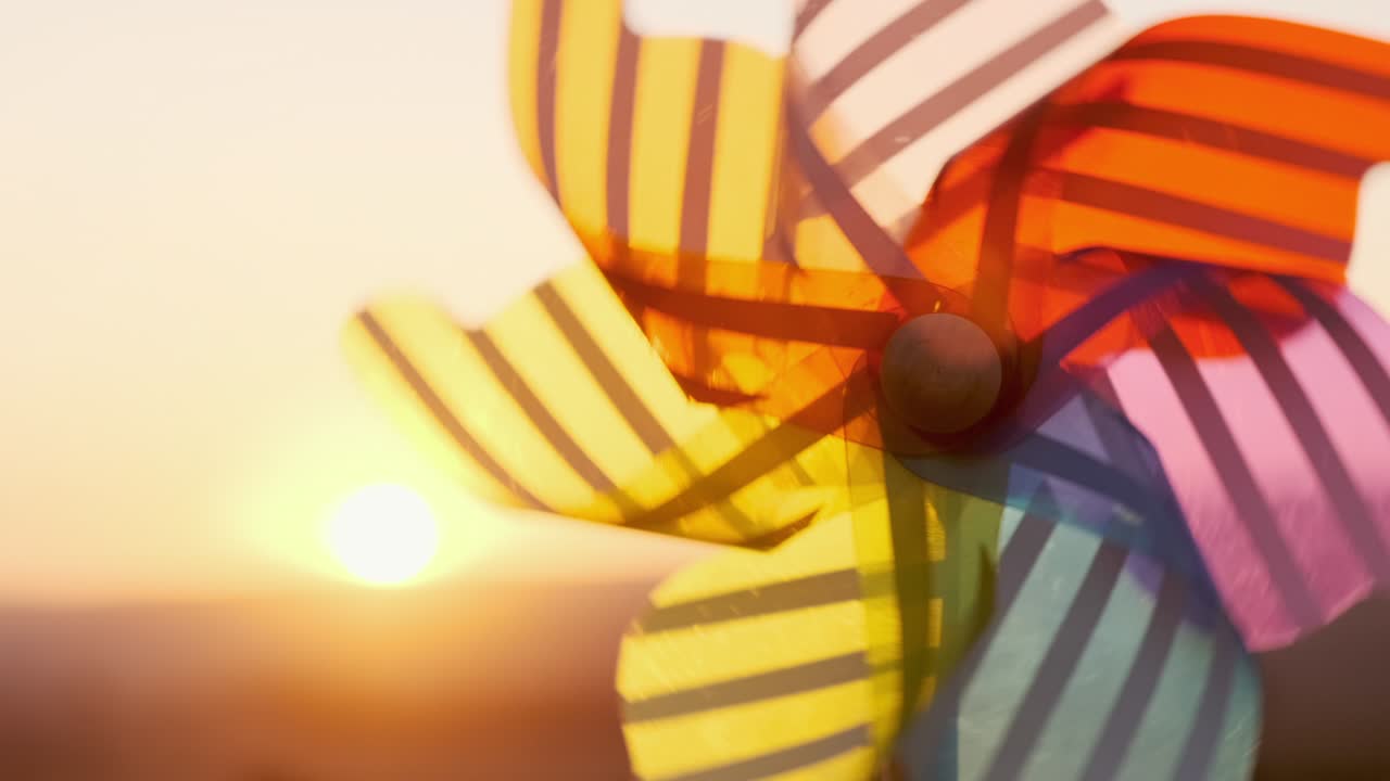 rueda giratoria plástico de color, molino de viento con viento soplando contra el cielo de la puesta de sol de un día soleado de verano. descendiendo disco brillante del sol más allá del horizonte en el campo con sol de trigo. lente flare. relajarse