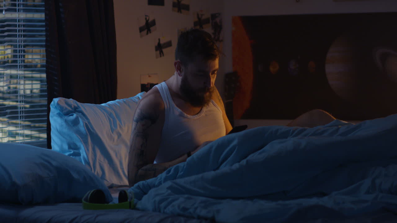 hombre usando teléfono inteligente en la cama por la noche
