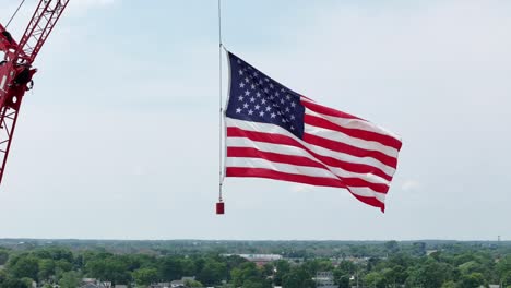 Hung-from-a-construction-crane,-the-flag-of-the-United-States-waves-in-the-wind