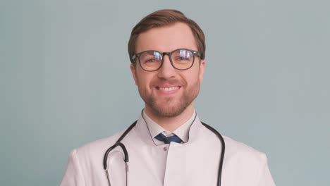 a doctor in a dress shirt is sitting at a desk, adjusting his glasses while using a laptop for vision care. he may also have a stethoscope nearby.