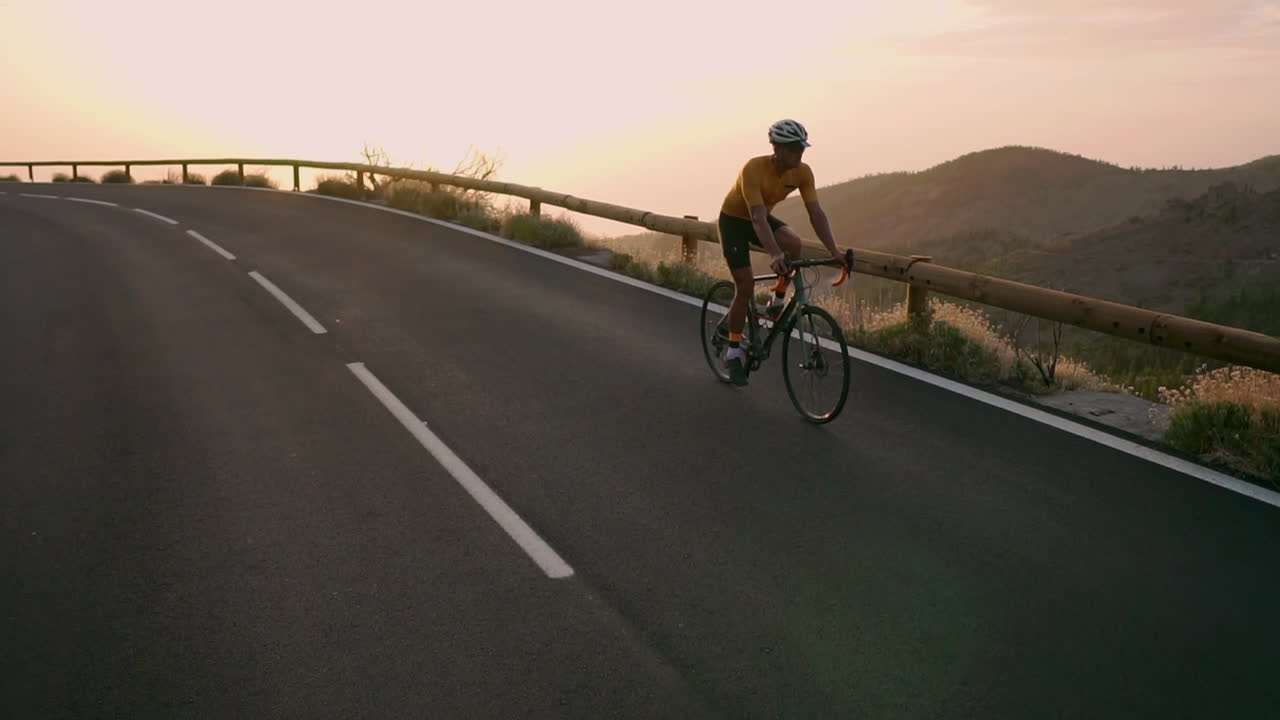 In slow motion, on a mountain serpentine, the athlete pedals away while beholding a captivating island view, illustrating the spirit of a healthy lifestyle