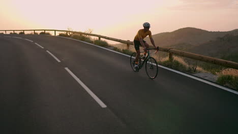 In-slow-motion,-on-a-mountain-serpentine,-the-athlete-pedals-away-while-beholding-a-captivating-island-view,-illustrating-the-spirit-of-a-healthy-lifestyle