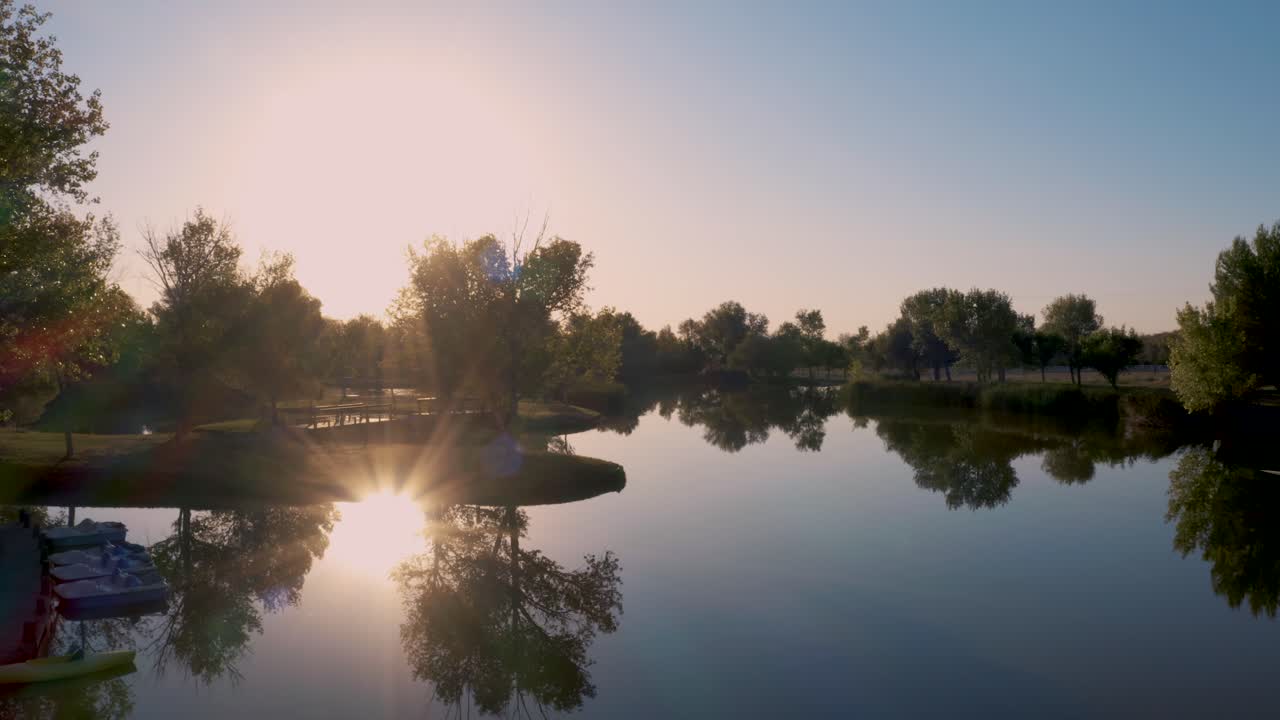 volando sobre un lago tranquilo al atardecer con un sol brillante reflejándose en el agua, empuje aéreo