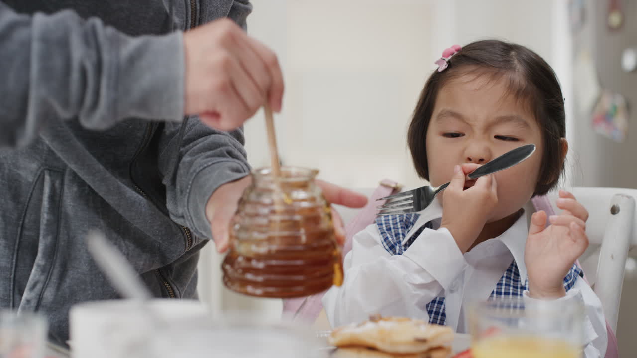 una niña asiática linda desayunando padre preparando gofres para su hija disfrutando de una deliciosa comida casera en la cocina en casa preparándose para la escuela 4k