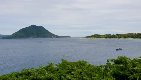 Scenic-view-overlooking-ocean-with-small-fishing-boat-and-volcanic-tropical-island-on-Alor-Island-in-Lesser-Sunda-Islands-of-East-Nusa-Tenggara,-Indonesia