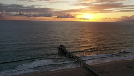 sunset over the ocean from manhattan beach pier with roundhouse aquarium in california, usa