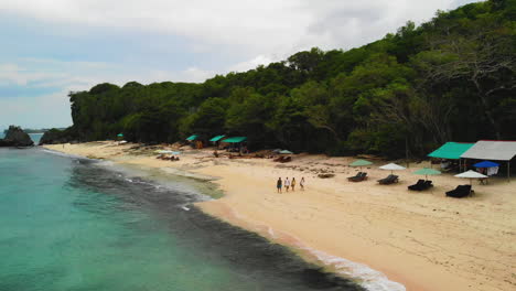 Drone-video-of-four-people-walking-at-an-amazing-white-sand-beach,-shot-in-Bali,-Indonesia