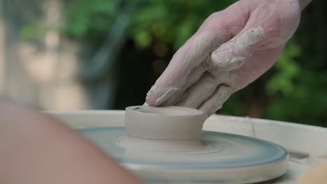 close up of hands working with clay on a potter's wheel. craftsman shapes a clay product on a potter's wheel