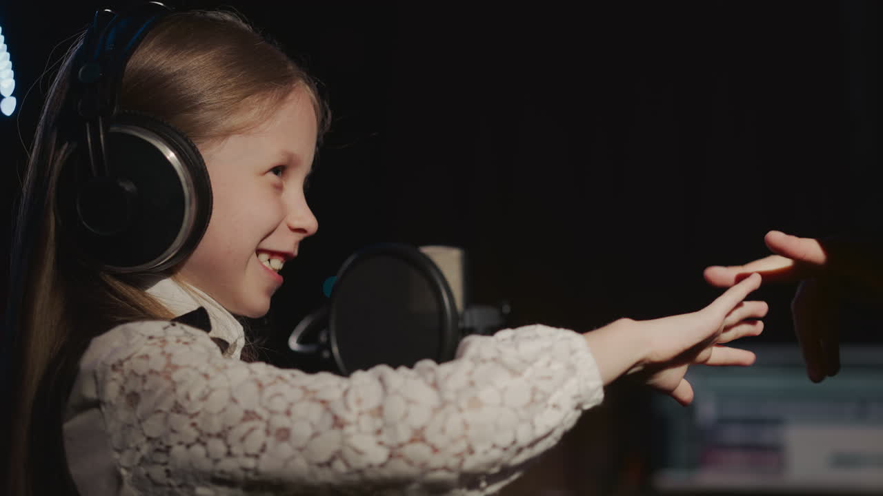 niño y entrenador juegan gestos en el estudio de música. niña sonriente recibe apoyo del maestro antes de la grabación de la pista de audio en el centro de arte. lección divertida