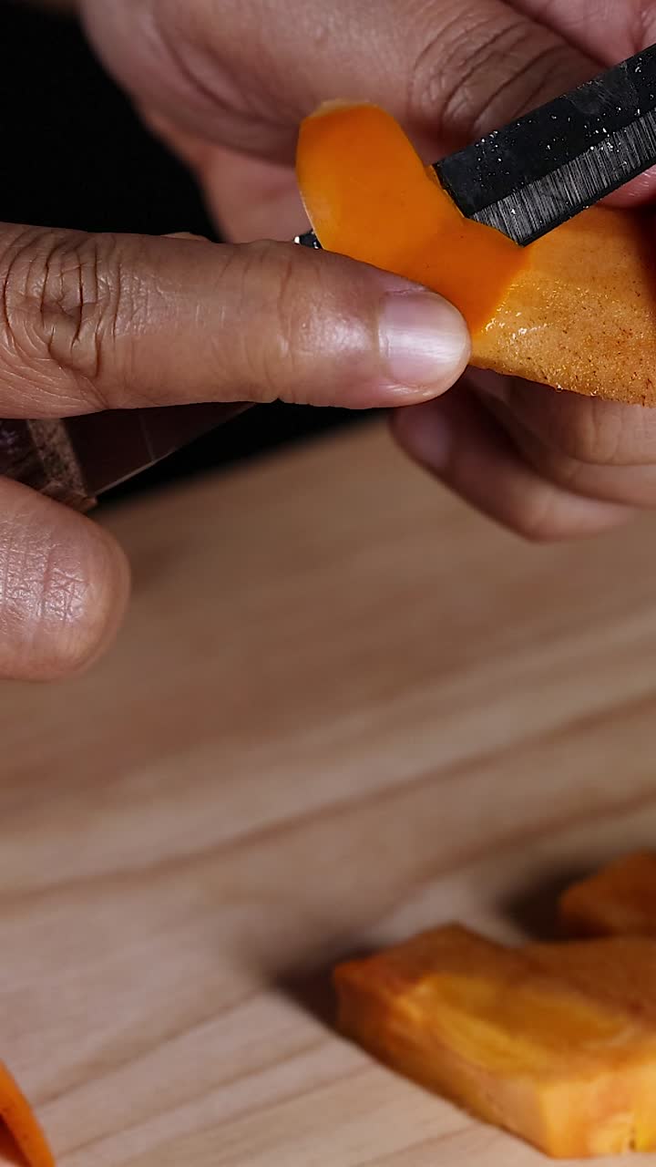 Hands slicing persimmon on wooden cutting board