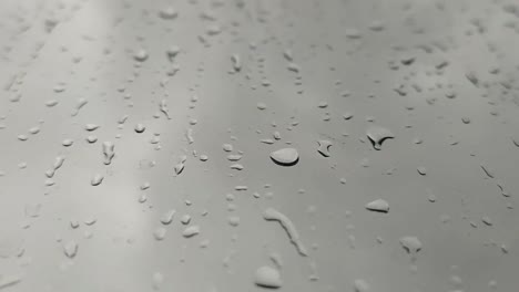 raindrops fall gradually down a vertical glass surface, guided by gravity. their slow descent captures the essence of rain's delicate movement.