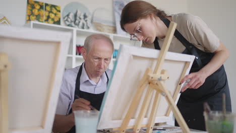 senior man with friends draws a picture. the old man's club is having fun and painting together.