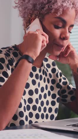 young positive african american business woman talking on phone sits in office