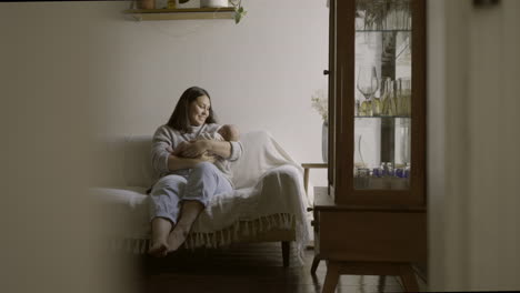 mother holding her newborn baby on the sofa