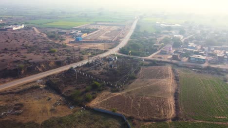 tomada aérea de un avión no tripulado de una planta de electricidad o energía de pequeña capacidad a lo largo de una carretera de un pueblo en madhya pradesh, india
