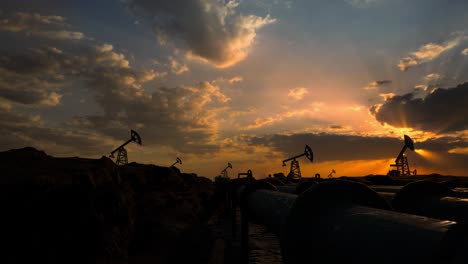 pipeline and working oil pump jacks in a against sunset extracting crude oil. pumping fossil oil is one of the methods of energy generation from renewable energy sources