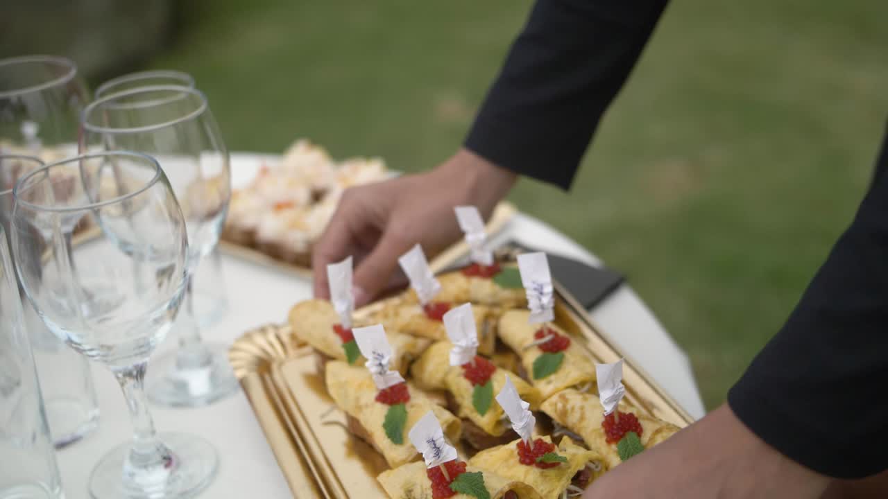 mujer sirviendo catering en una bandeja dorada en un evento de celebración en el jardín
