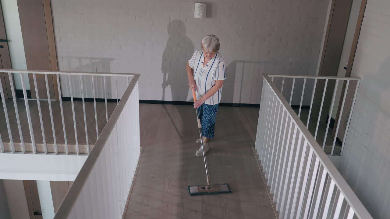 mujer anciana limpiando el piso del pasillo